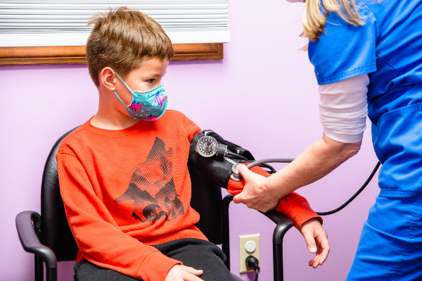 kid wearing mask getting his blood pressure taken